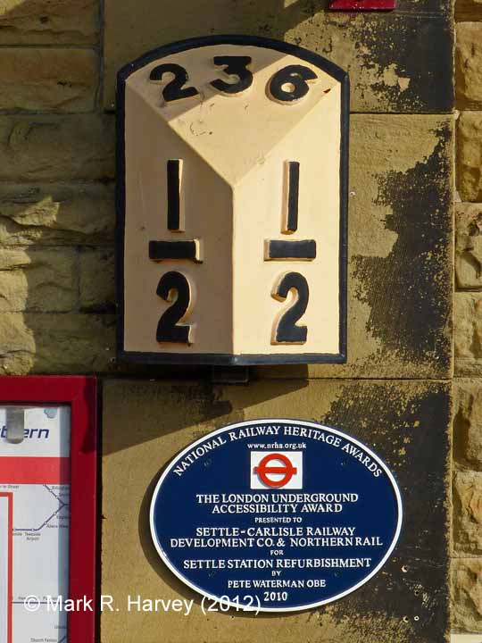 Settle Station Booking Office: wall-mounted milepost (236½) and NRHA plaque"