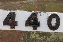 Close-up of "440" numerals showing that each number is fixed to wooden arm via two screws.